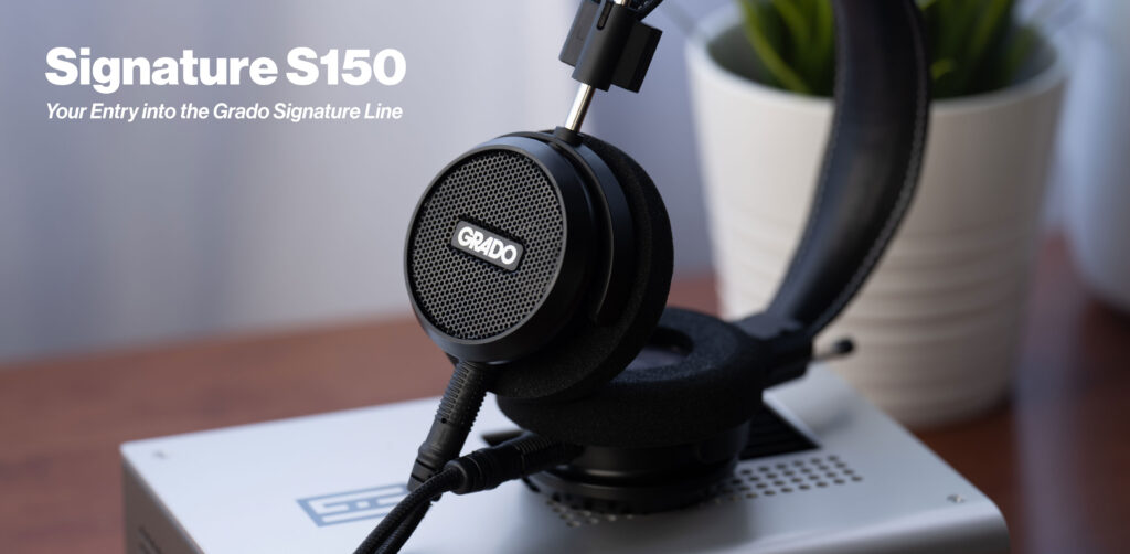 Grado Signature S150 liegt auf einer Ohrmuschel auf einem Holztisch, oben links der Schriftzug Signature S150