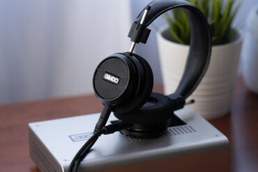 Grado Signature S150 liegt auf einem silbernen Kopfhörerverstärker auf einem Holztisch