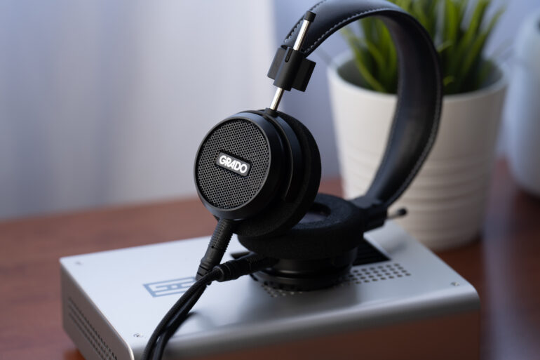 Grado Signature S150 liegt auf einem silbernen Kopfhörerverstärker auf einem Holztisch
